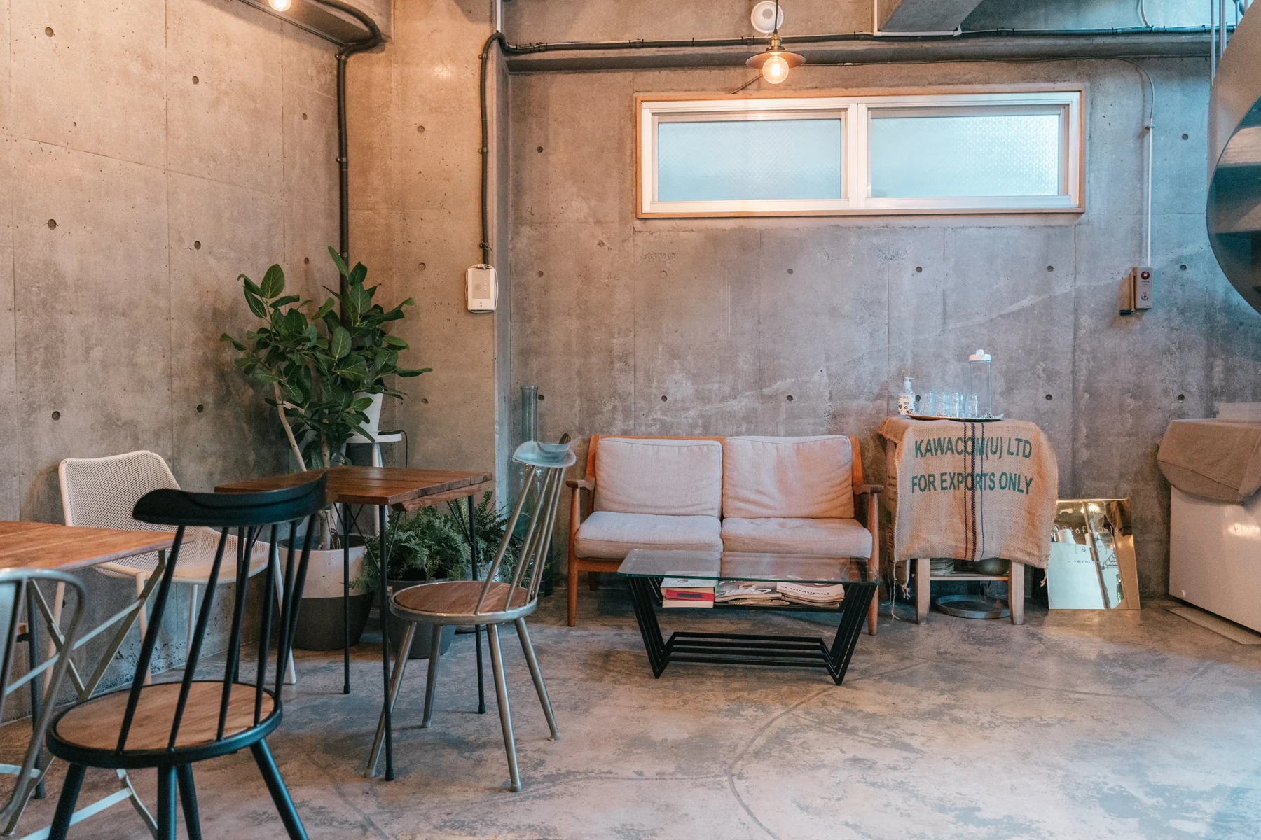 コンクリートの壁と木の家具がある［&:C］tokyo coffeeの店内